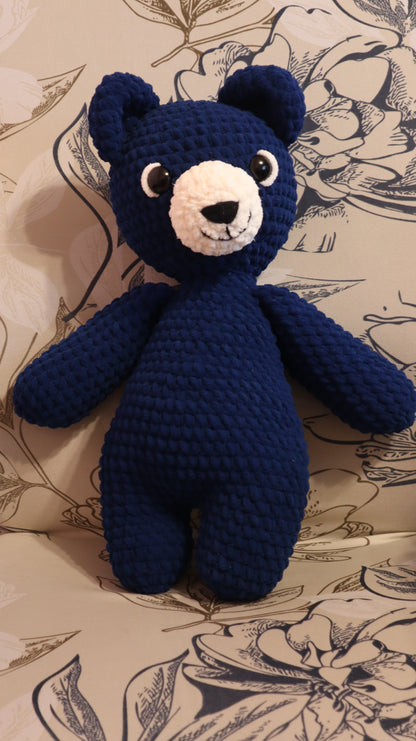 Dark Blue crocheted bear on a floral-patterned fabric background