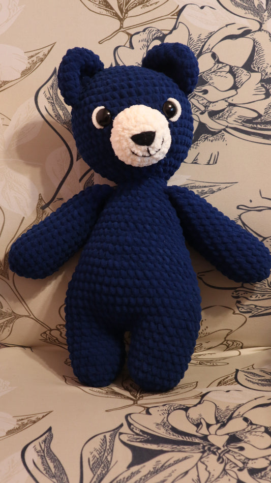 Dark Blue crocheted bear on a floral-patterned fabric background