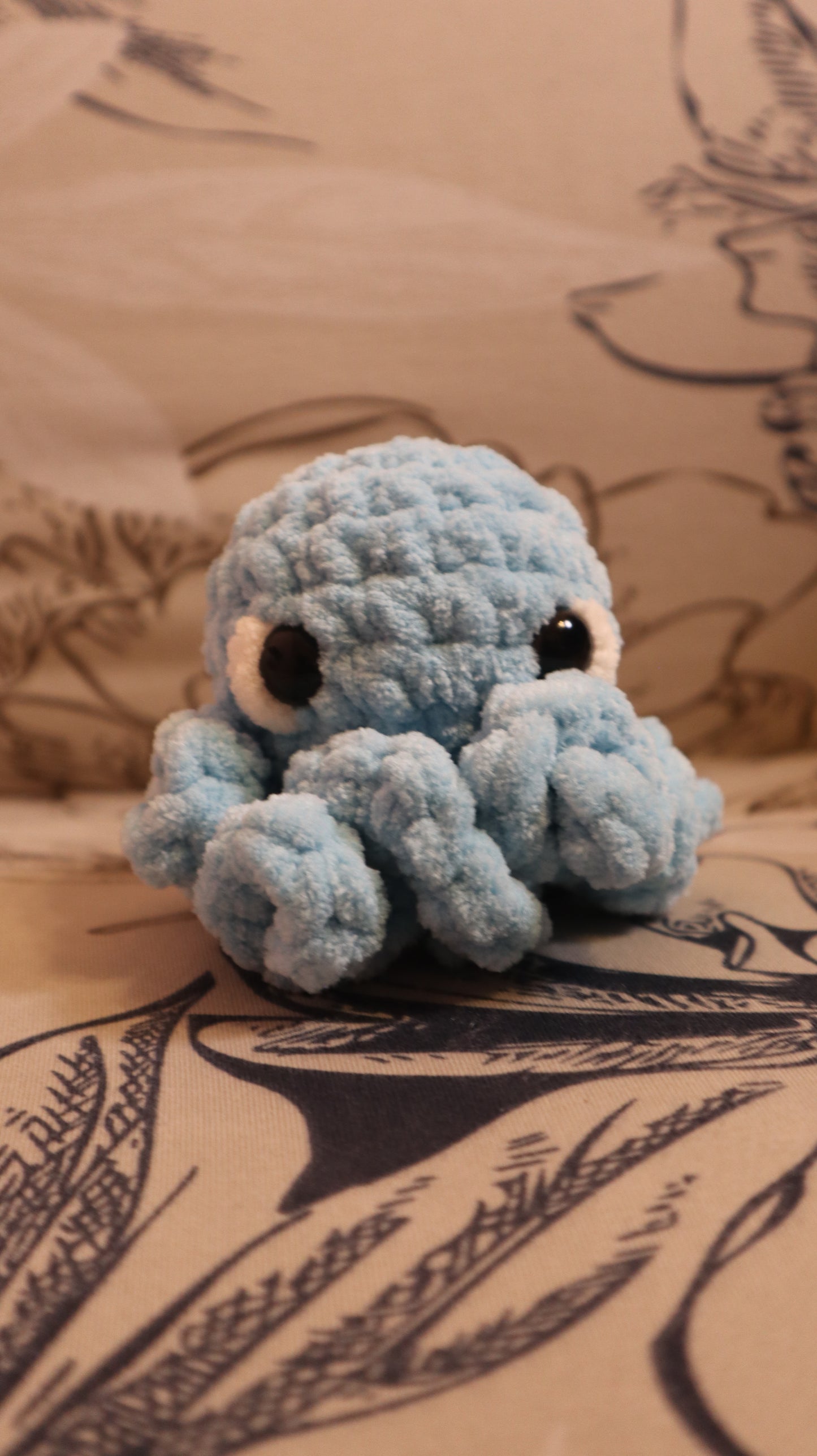 Light Blue Crocheted Octopus plushie on a floral fabric background